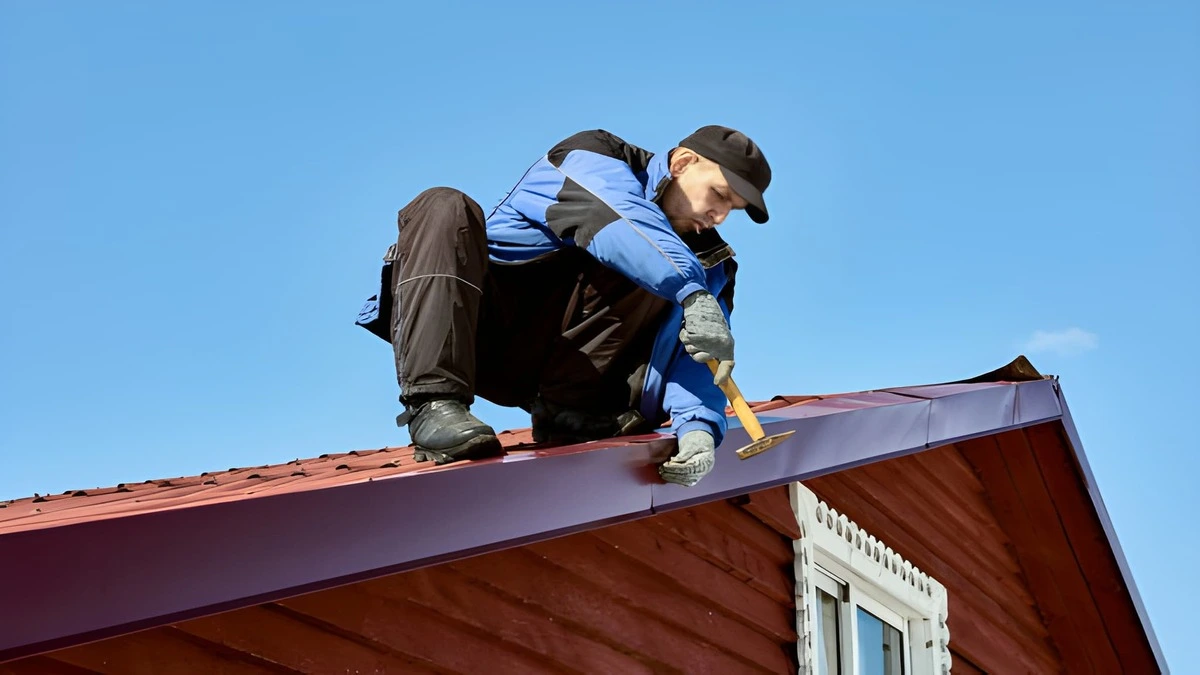 Completed tin roof installation - Inspector checking exposed fastener screw EPDM washers and ridge cap sealant on corrugated metal residential roof - Metal roof maintenance