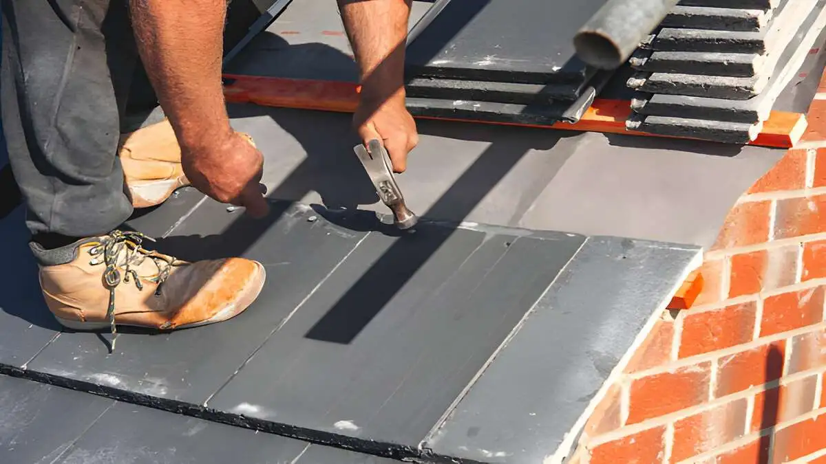 How to repair a slate roof hook method, contractor sliding replacement natural slate tile into position over copper slate hook fastener on residential roof, slate roof repair installation 2026