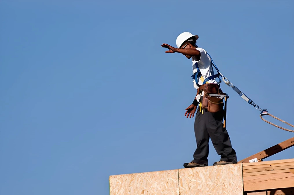Roofing labor shortage 2026 solution, experienced roofing foreman training young apprentice installer on residential roof showing correct shingle fastening technique, roofing workforce pipeline development