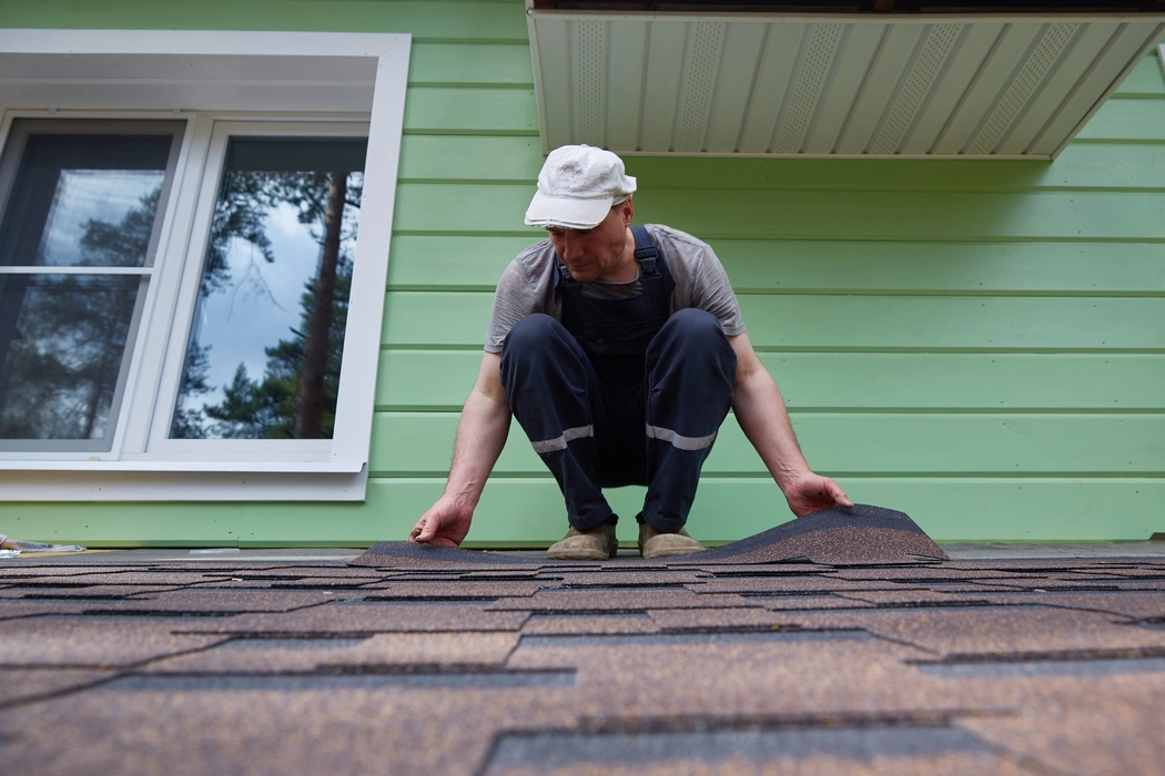 Roofer installing asphalt shingles on a residential home in 2026