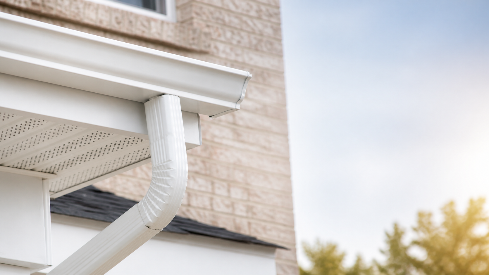 White gutter and downspout installed on a Denver home roofline.