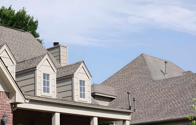 An aerial view of a house with newly installed asphalt shingles.