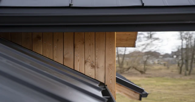 Workers installing OSB metal roof sheathing panels on a sloped roof deck before corrugated metal panels are applied